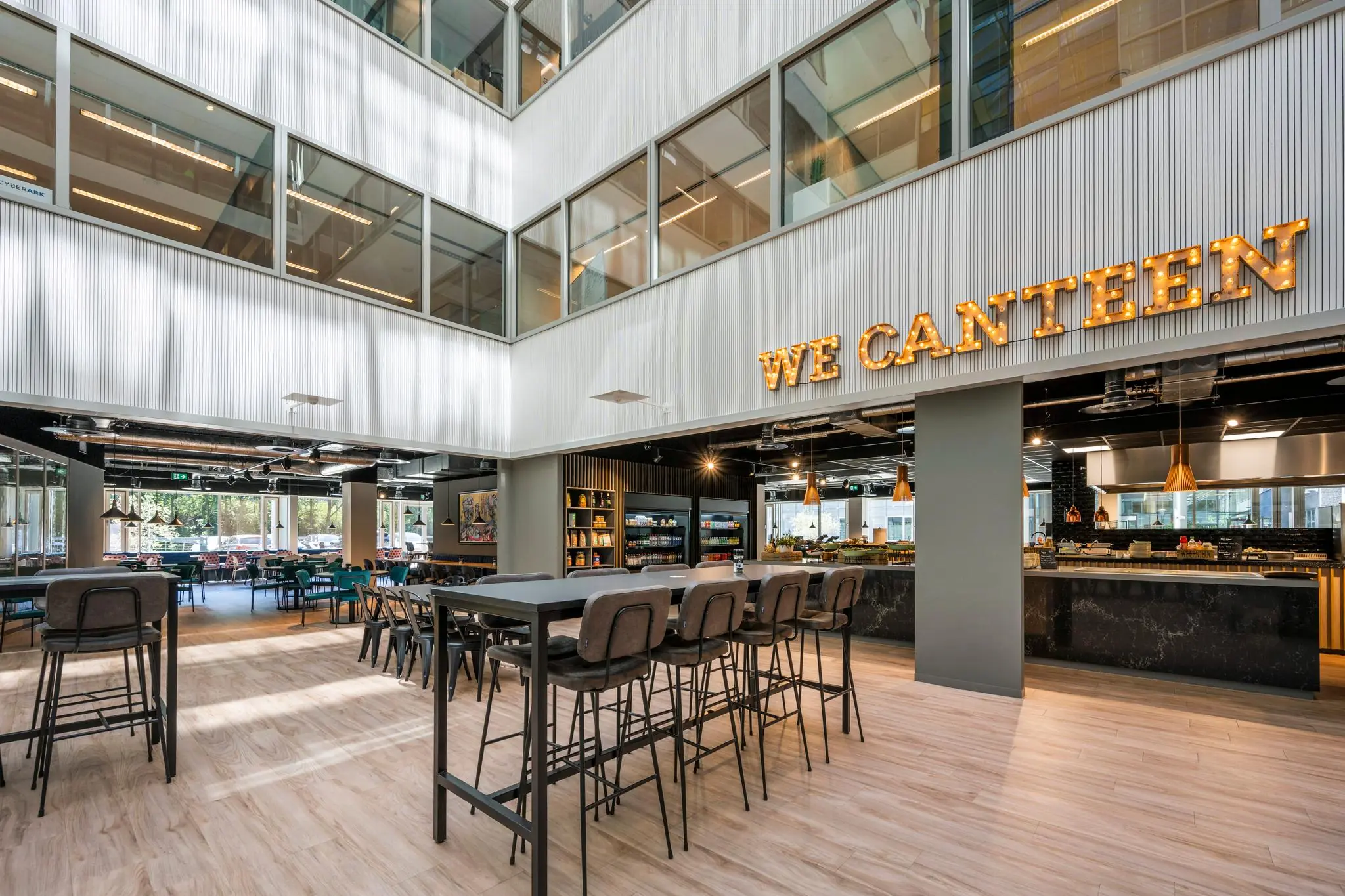 Moderne bedrijfsrestaurant "We Canteen" met hoge plafonds, grote ramen en zitgelegenheid aan de Thomas R. Malthusstraat.